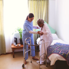 caregiver helping the elderly woman stand