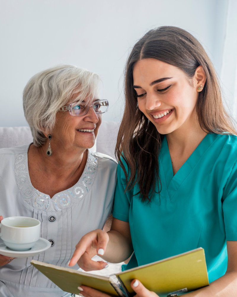 caregiver and elderly woman looking at the book