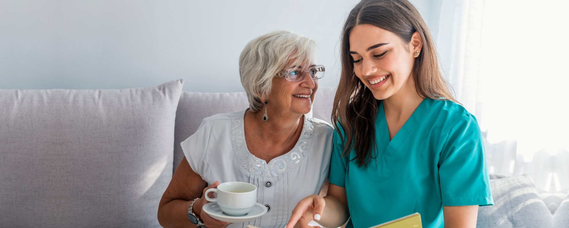 caregiver and elderly woman looking at the book