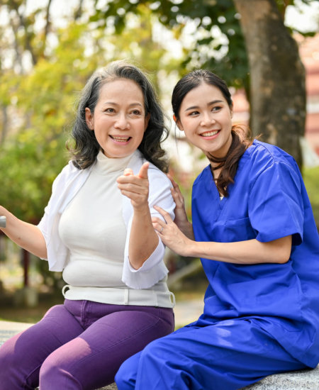 caregiver and elderly woman sitting in the park