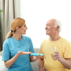 caregiver giving medicine to the elderly man