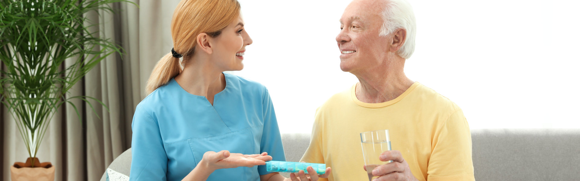 caregiver giving medicine to the elderly man