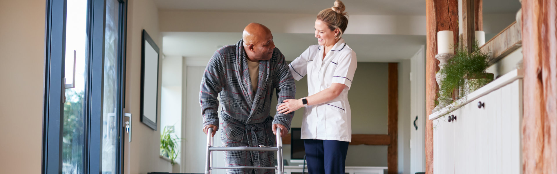 caregiver and elderly man walking inside the house