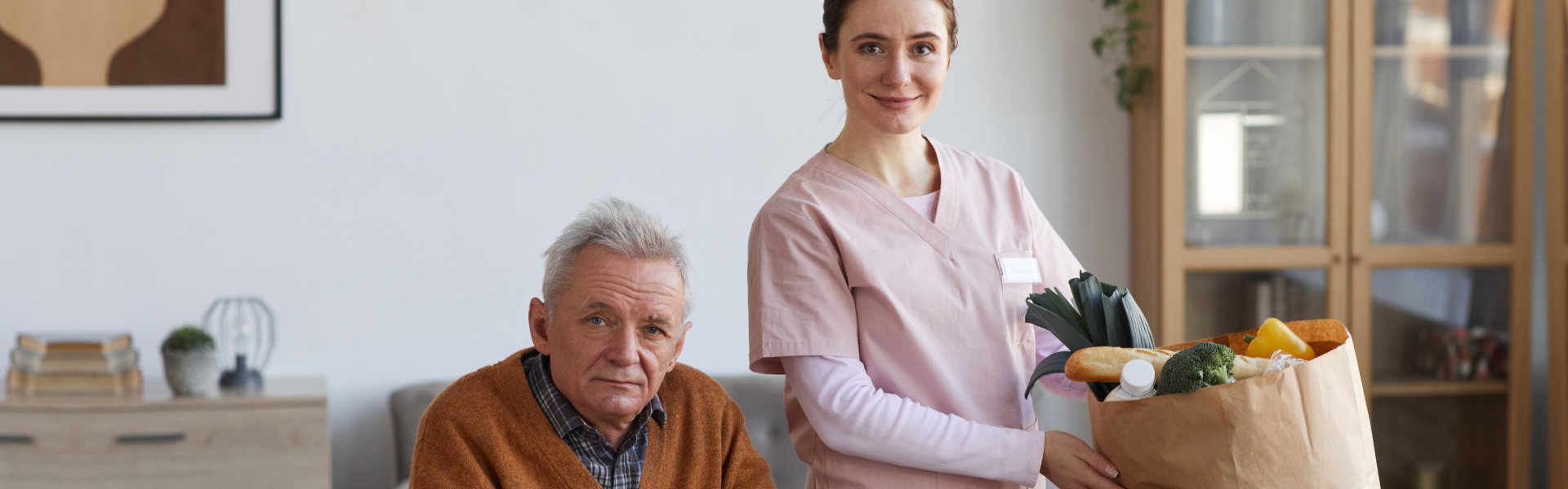 elderly man and caregiver holding a grocery bag