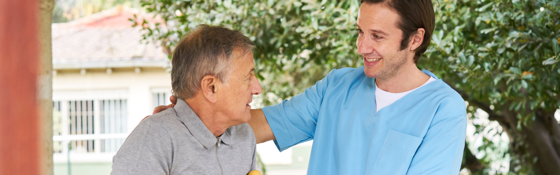 caregiver and elderly man walking outside the house