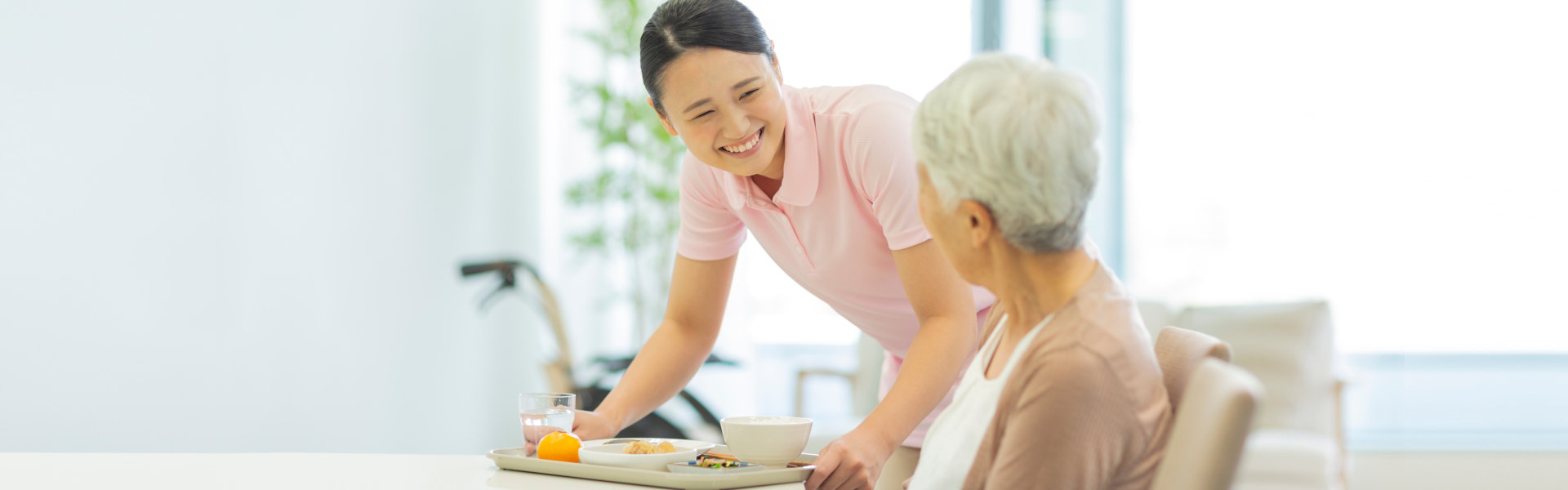 caregiver bringing food for the elderly woman