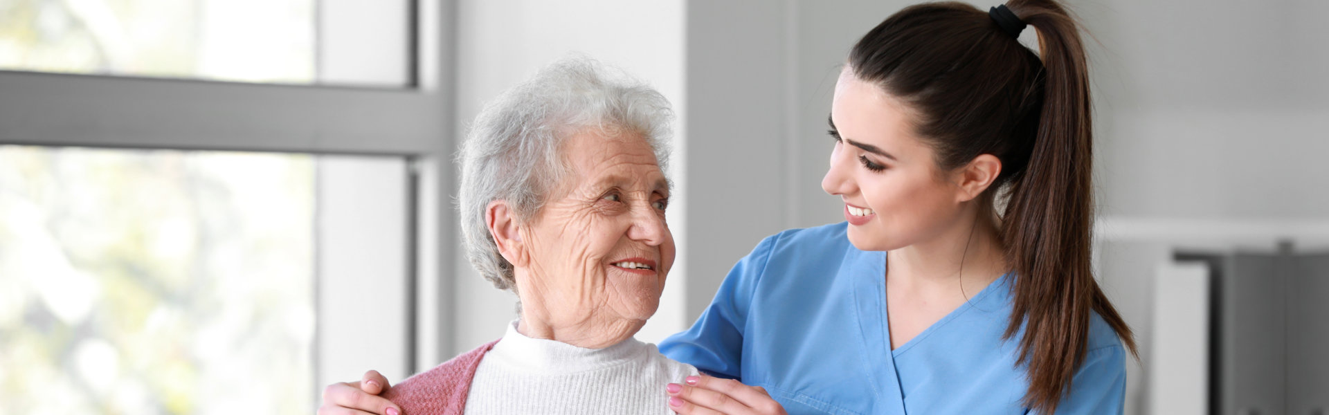 caregiver smiling while looking at the elderly woman